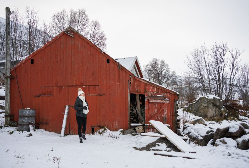 Solitary woman in front of red house in snowy landscape