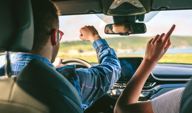 Young man and girlfriend dancing while driving a car