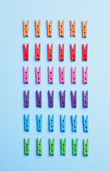 Rainbow colored clothes pins on light blue background