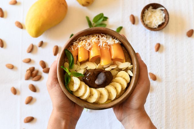 Crop person holding bowl with fruits and seeds