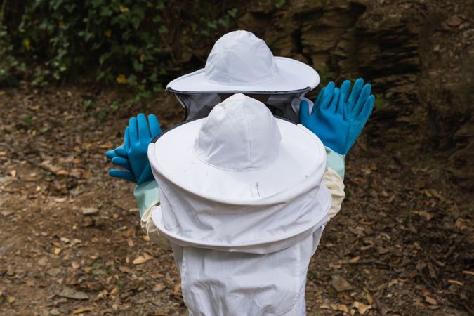Faceless group of children in protective uniform in apiary