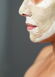 Crop woman with drying clay mask