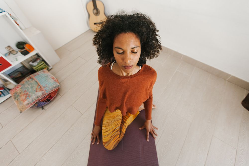 Sportive woman performing yoga pose in room