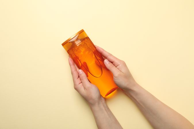 Female hands hold shampoo bottle on beige background, space for text