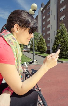 Sportive woman with fixie bike looking smartphone