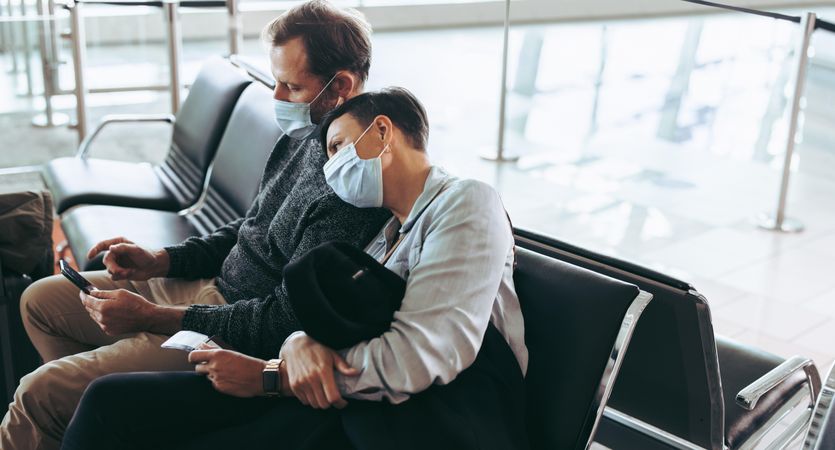 Man and woman traveler during pandemic sitting at airport terminal