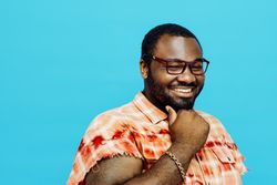 Smiling man in blue studio shoot with hand on chin