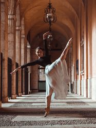 Graceful ballerina stretching raised forward leg in archway