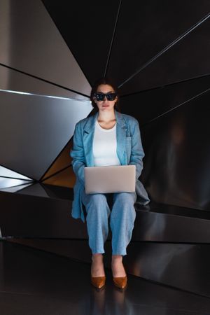 Woman in sunglasses browsing laptop in studio