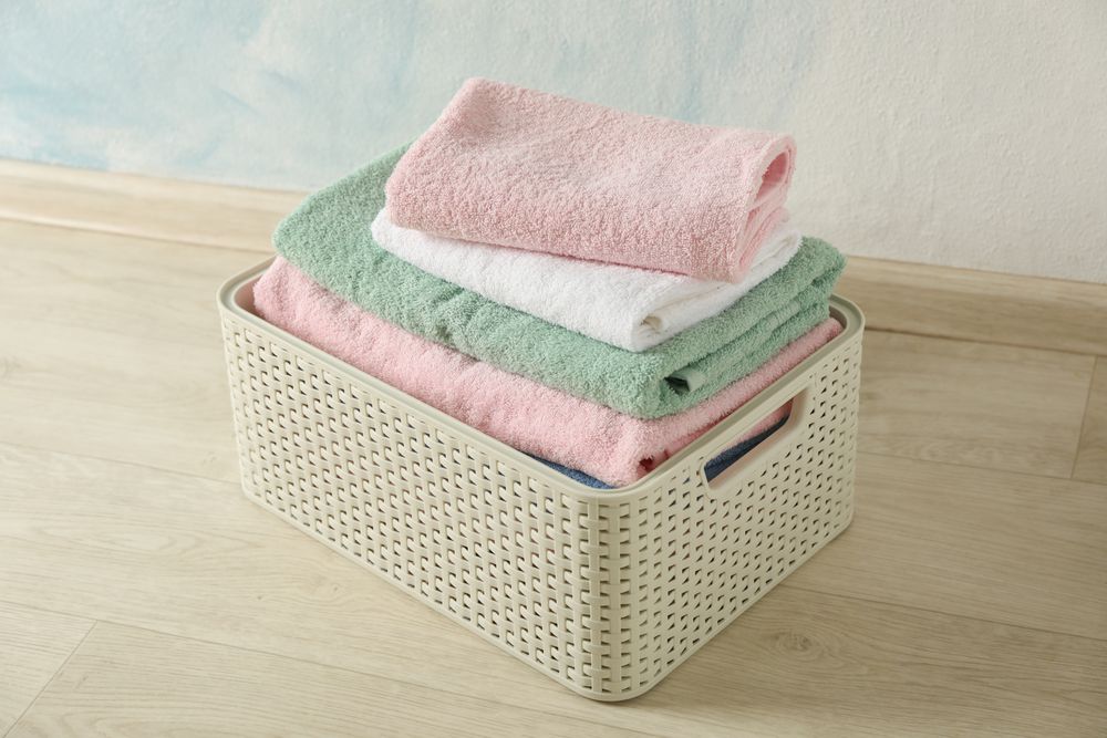 Basket with clean laundry on textured floor, space for text