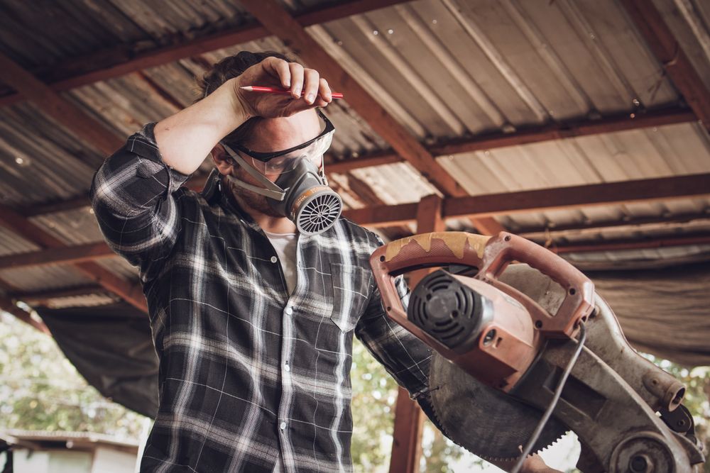 Carpenter tired from work using electric saw in workshop