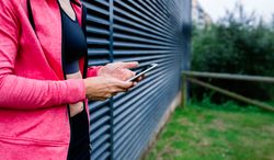 Unrecognizable female athlete with mobile phone