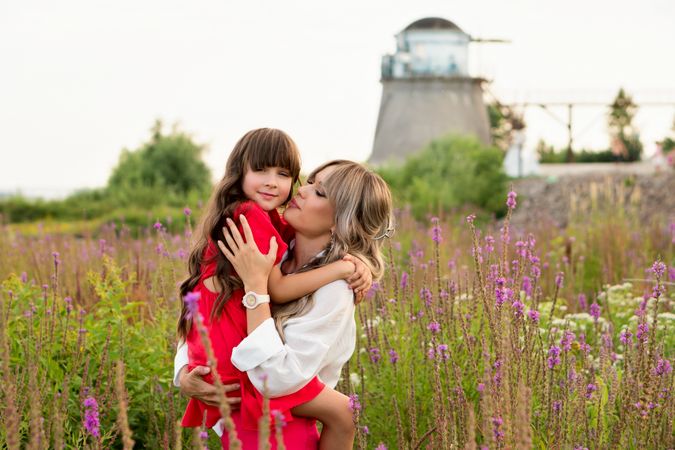 Mom and little daughter walking among meadow flowers