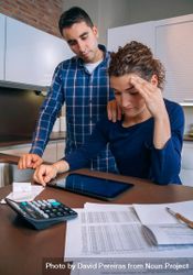Stressed couple going through their bills together in the kitchen, vertical bD9280