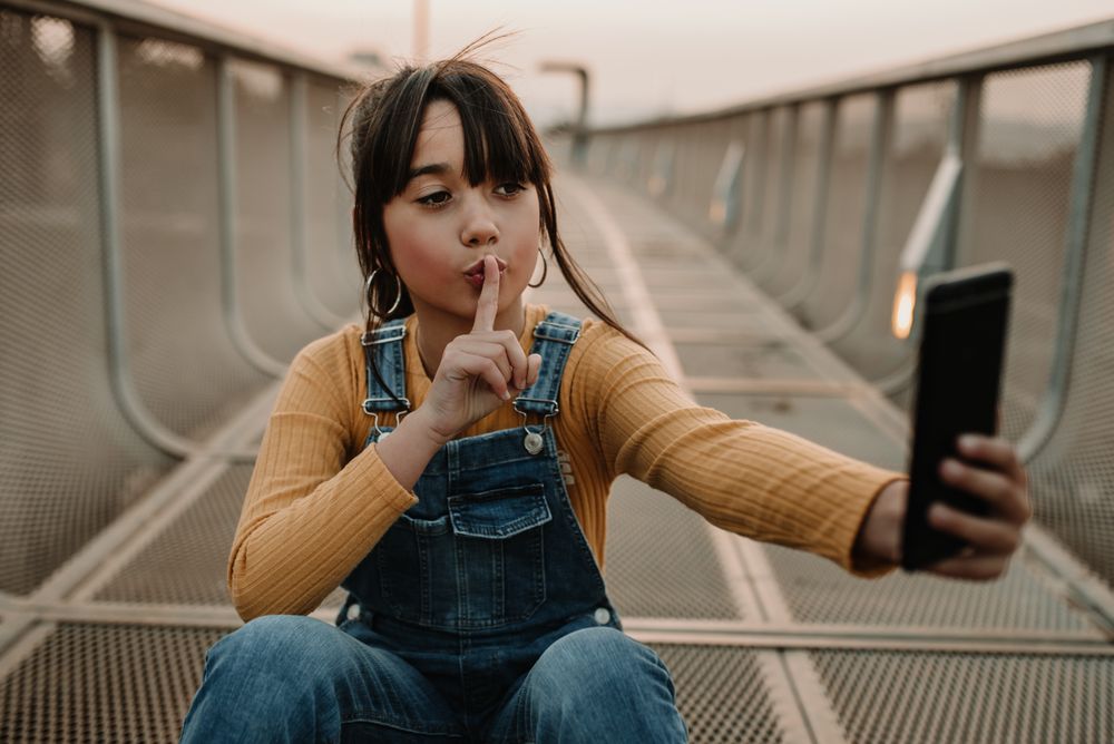 Funny girl taking selfie on smartphone on walkway