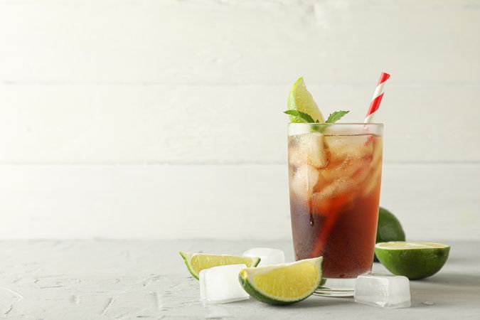 Glass with cold cola and citrus on grey cement background, space for text