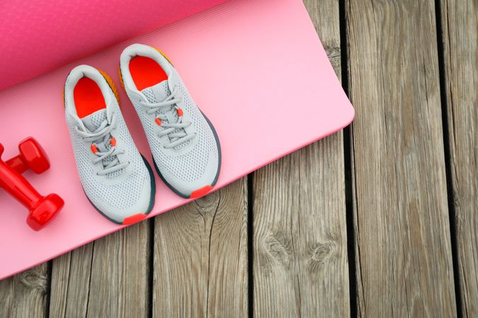 Karemat, sneakers and dumbbells on wooden background, space for text