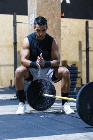 Strong Hispanic sportsman near barbell