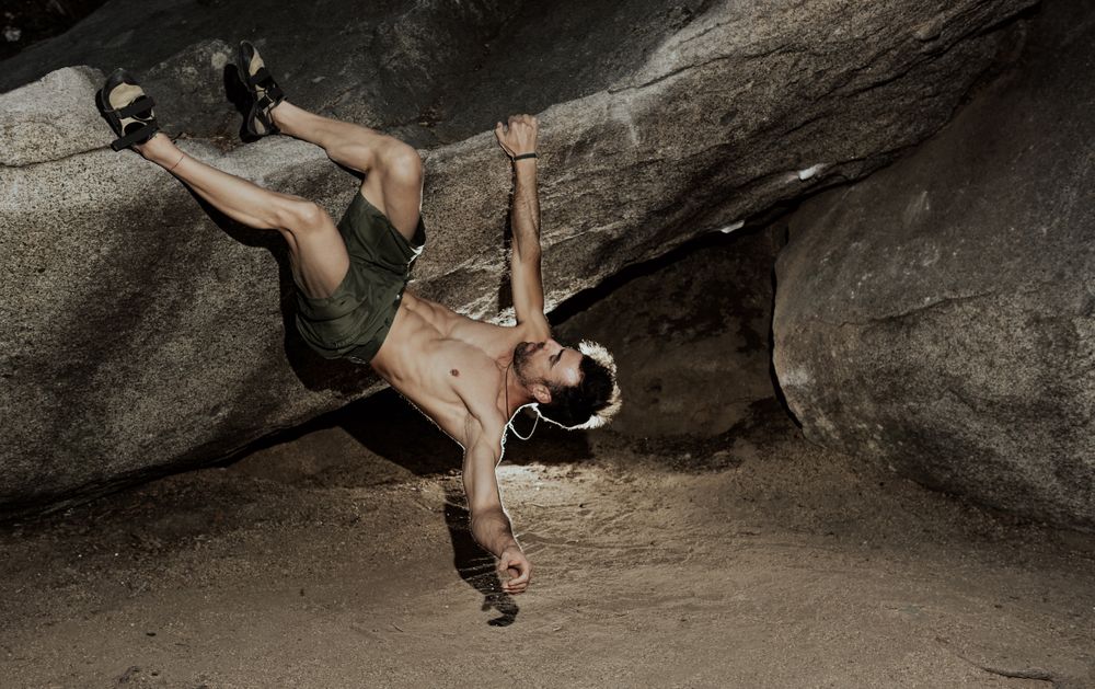 Man practicing rock climbing among large rocks in a forest