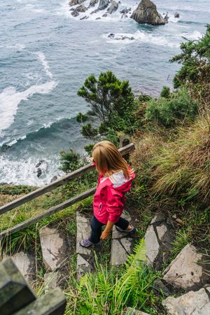 Woman walking down on stone steps leading down to foamy sea