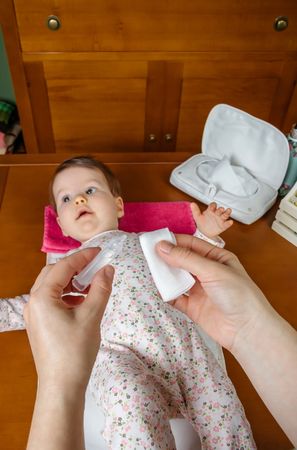 Closeup of woman's hands pouring physiological serum in a cotton to clean the eyes of baby