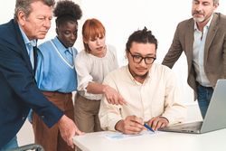 Multi-ethnic team standing around developer's desk