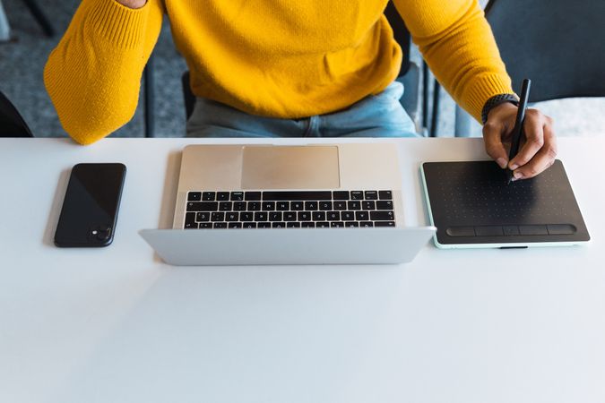 Anonymous Black man working on laptop with tablet