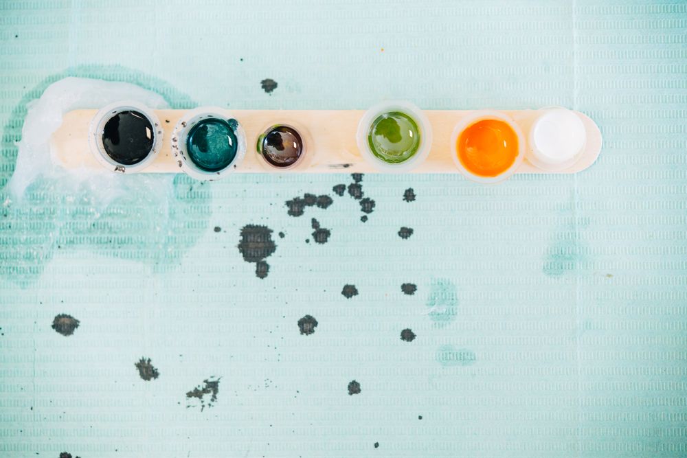 Top view of row of ink pots on blue paper