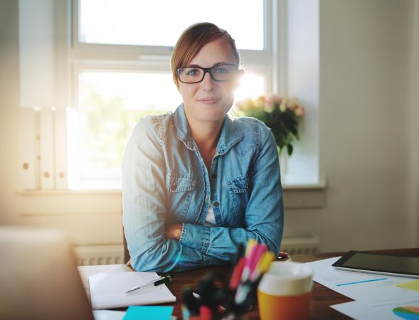 Confident female entrepreneur sitting at her desk in her bright home office