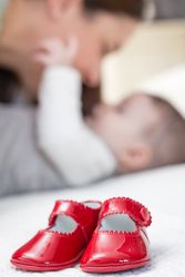 Baby red shoes pair and babe on the background