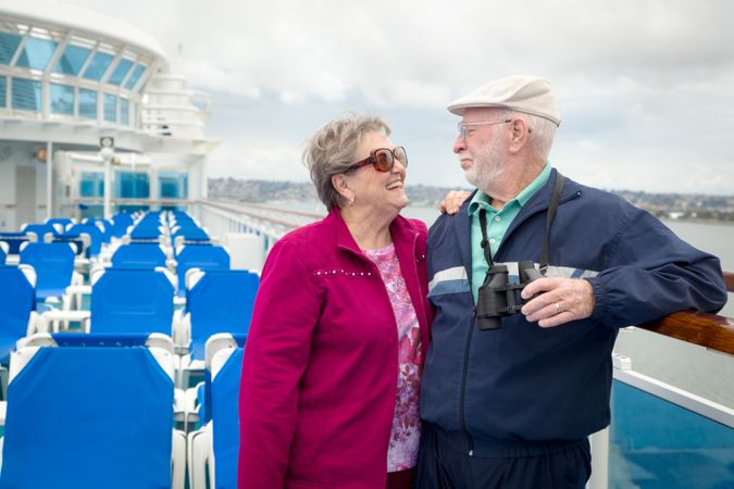 Loving Mature Adult Couple Enjoying The View From Their Passenger Cruise Ship with Their Binoculars.