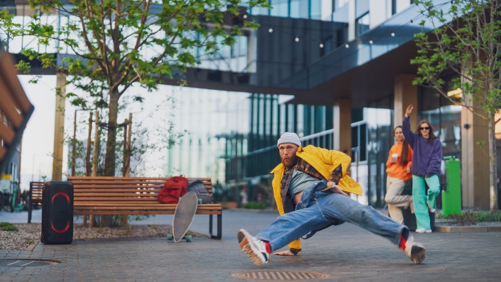 Vibrant Urban Scene Capturing A Young Man Breakdancing With Dynamic Energy, Surrounded By Friends Cheering