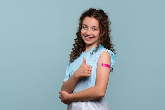 Smiling girl giving thumbs up after vaccination