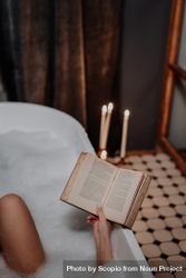 Cropped image of woman reading a book in the bathtub 4mKPX0