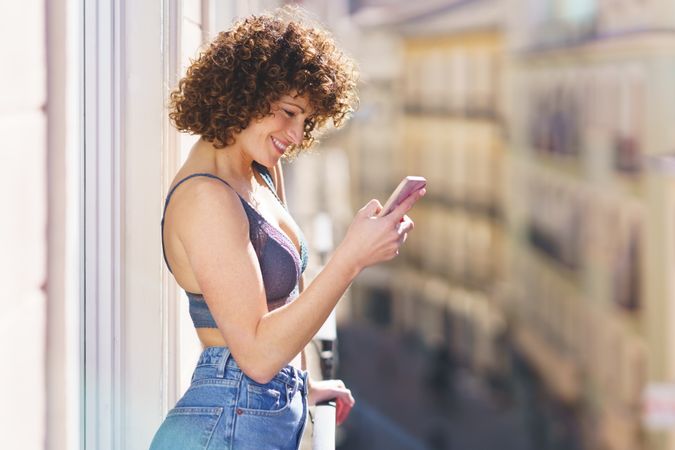 Smiling women checking phone on balcony