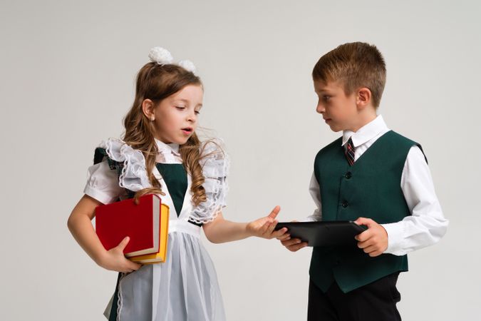 Portrait two elementary school children in uniform with books and tablet