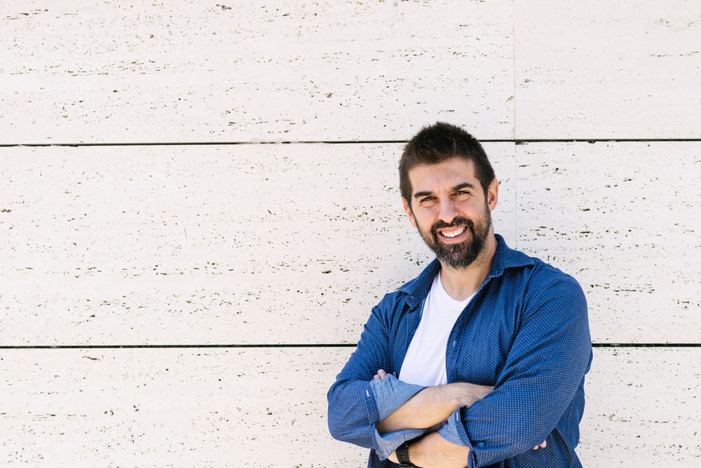 Smiling man in denim standing outside with arms crossed
