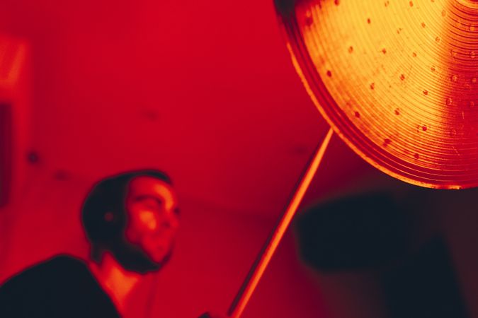 Man with drumsticks playing on drums in redness
