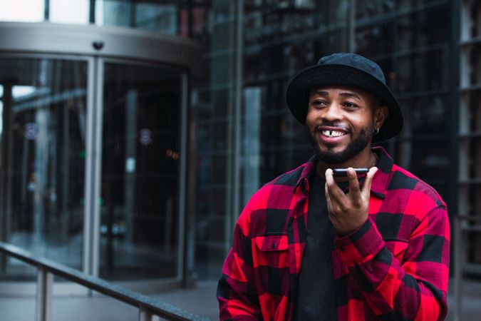 Cheerful Black man talking on smartphone on street