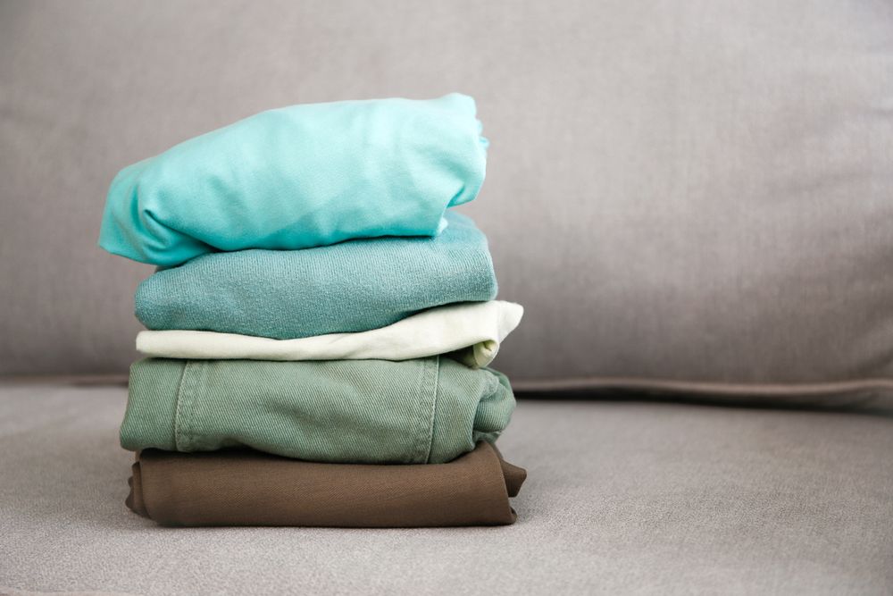 Pile of colorful warm clothes on the grey sofa.