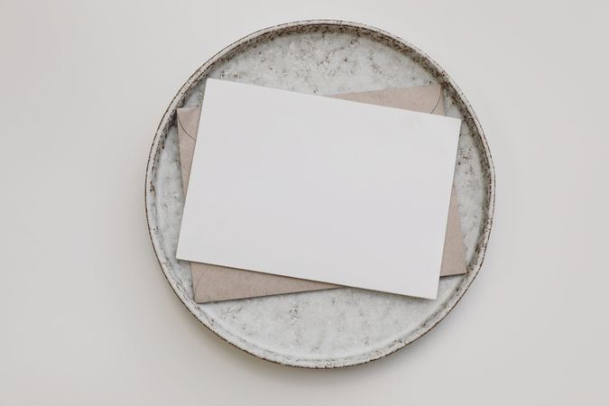 Blank paper invitation, craft envelope on ceramic plate on plate
