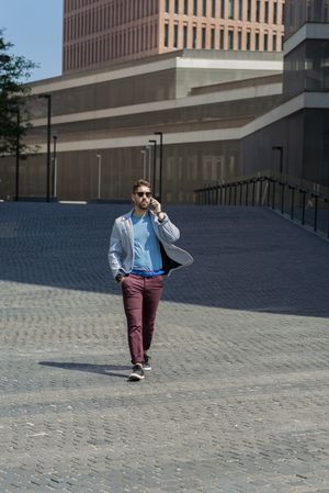 Modern businessman speaking by phone and walking outdoors