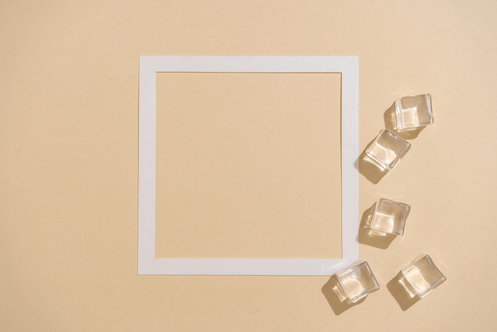 Flat lay of ice cubes on beige background with square