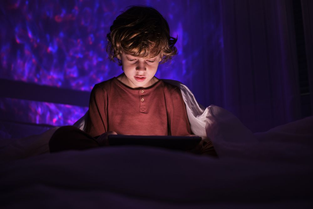 Calm boy watching video on tablet in darkness