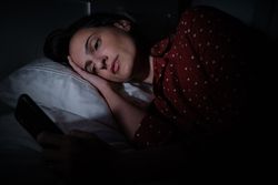 woman browsing smartphone in darkness