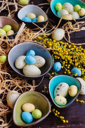 Easter holiday card with bowls of colorful eggs on table with straw