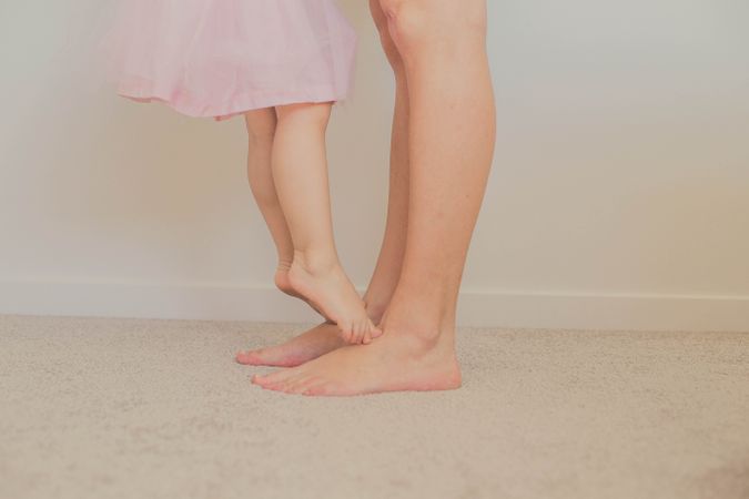 Barefooted girl standing on grown up feet