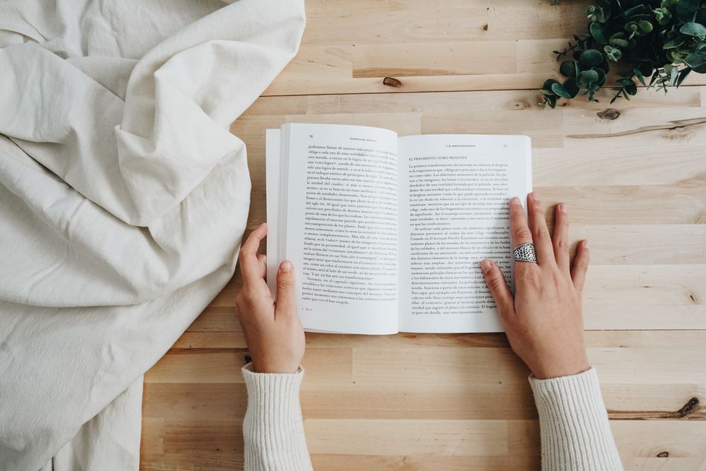 Top view of person in light sweater reading a book