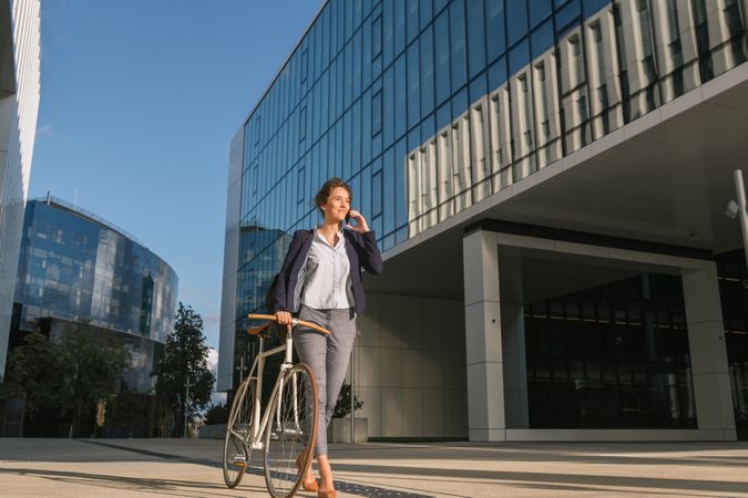 Cheerful manager with bicycle talking on smartphone