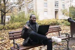 Digital Communication: Black Man Engaged in Online Chat via Laptop.